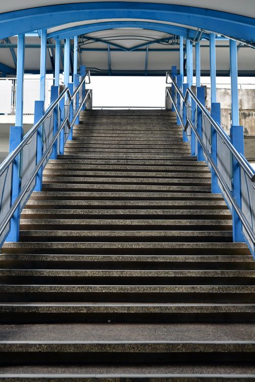 Free A perspective view of a concrete stairway with blue metal handrails in an urban setting. Stock Photo