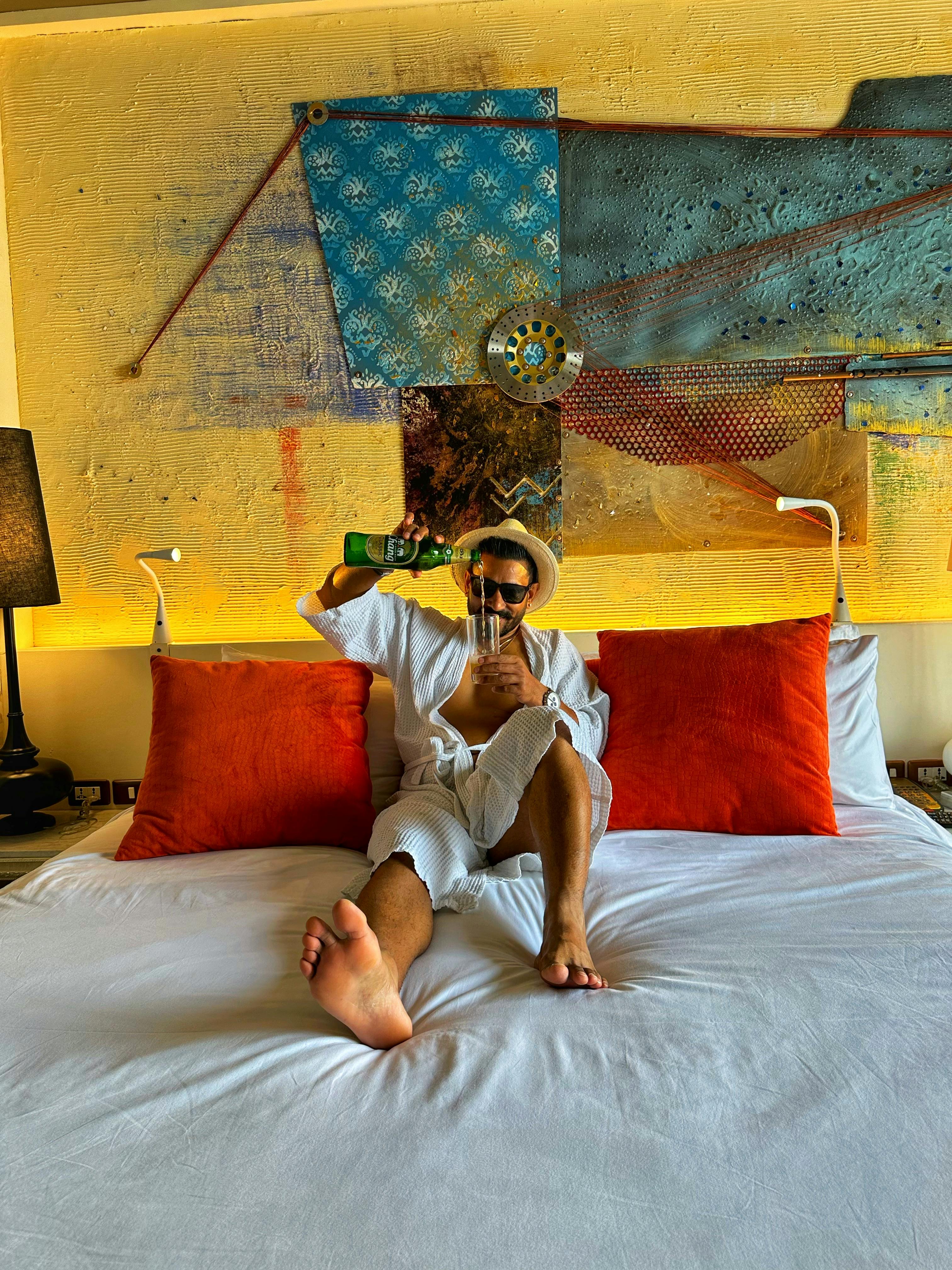Free Man in a hat pouring a drink while relaxing on a bed in Chonburi, Thailand. Stock Photo