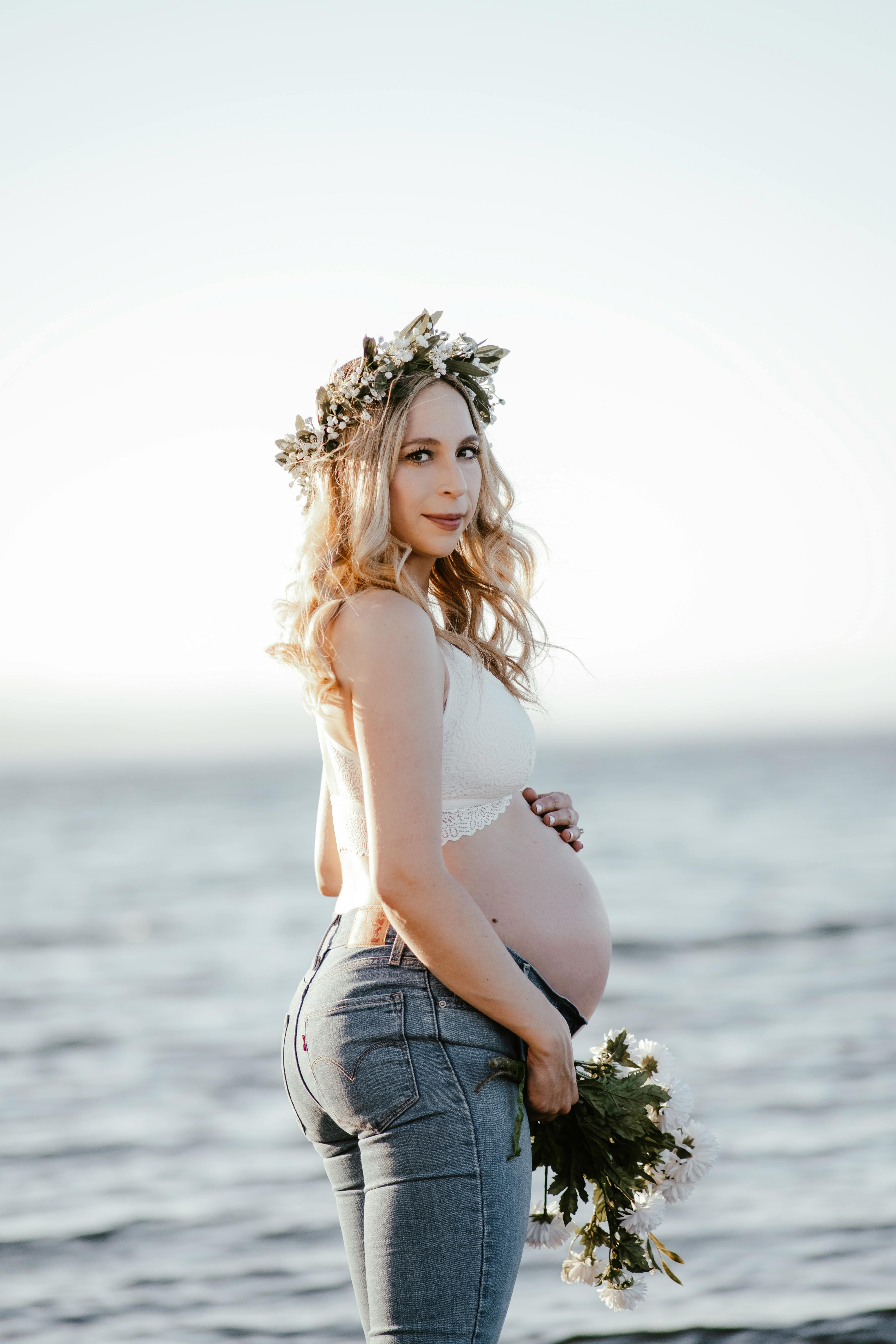 戴着花环的优雅孕妇在海边摆姿势