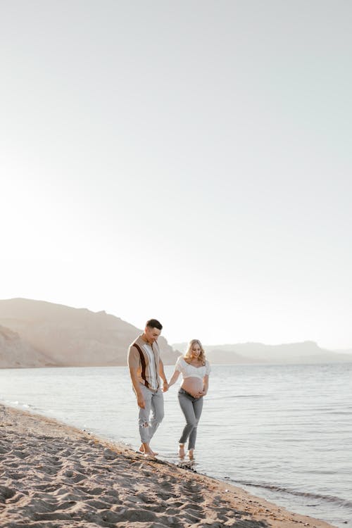 Pregnant Woman Walking with Man on Shore