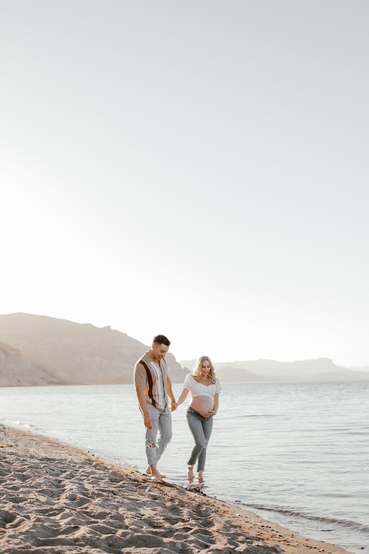 Pregnant Woman Walking With Man On Shore