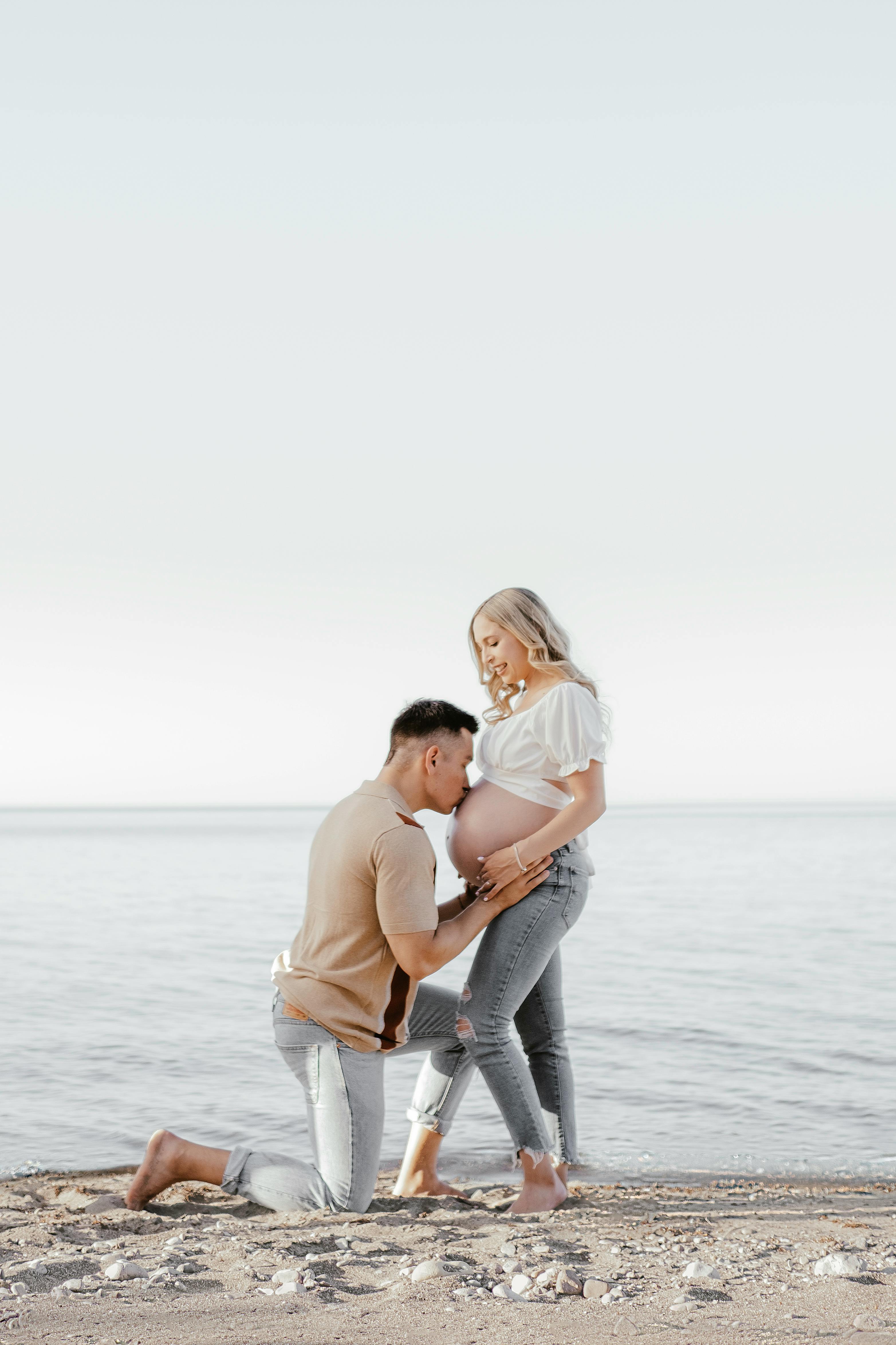 一对夫妇在宁静的海滩上庆祝怀孕，他们在那里进行充满爱意的互动