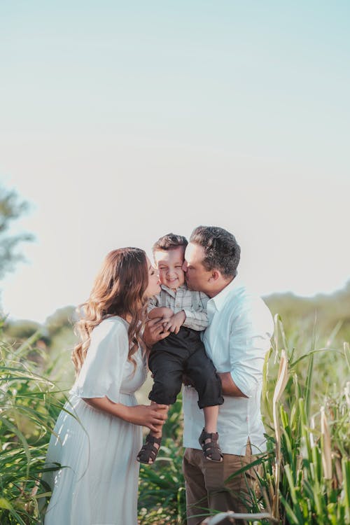 Free Couple Kissing Son on Field Stock Photo