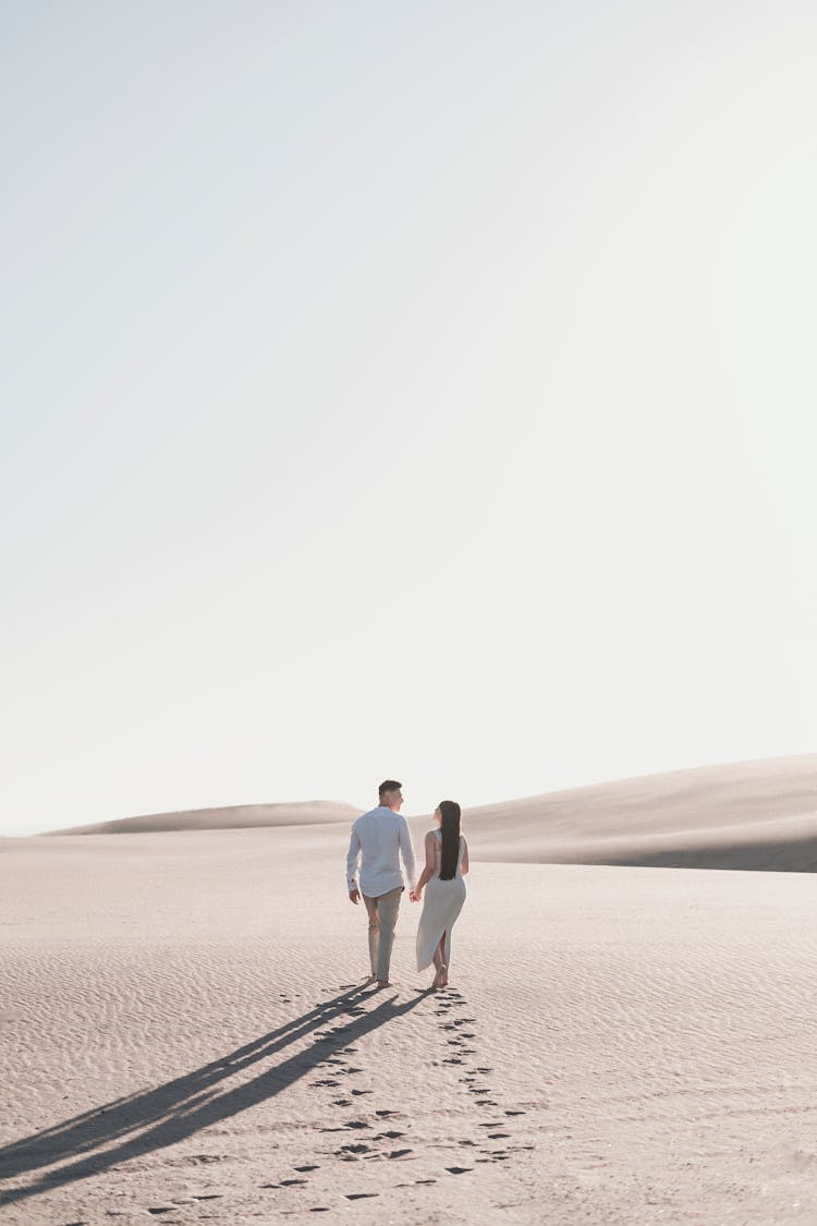 Couple Walking Together On Sunlit Desert