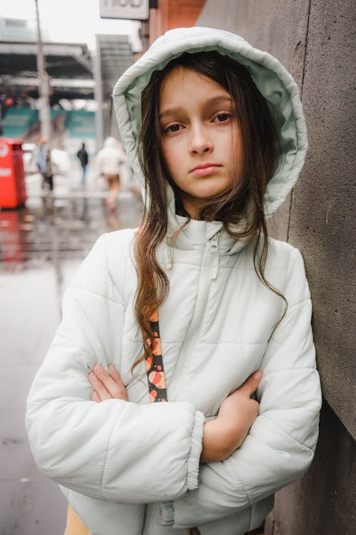 Girl in White Jacket Standing with Arms Crossed