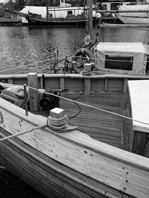 Free Black and white photo of a vintage wooden ship docked in a harbor, showcasing detailed craftsmanship. Stock Photo