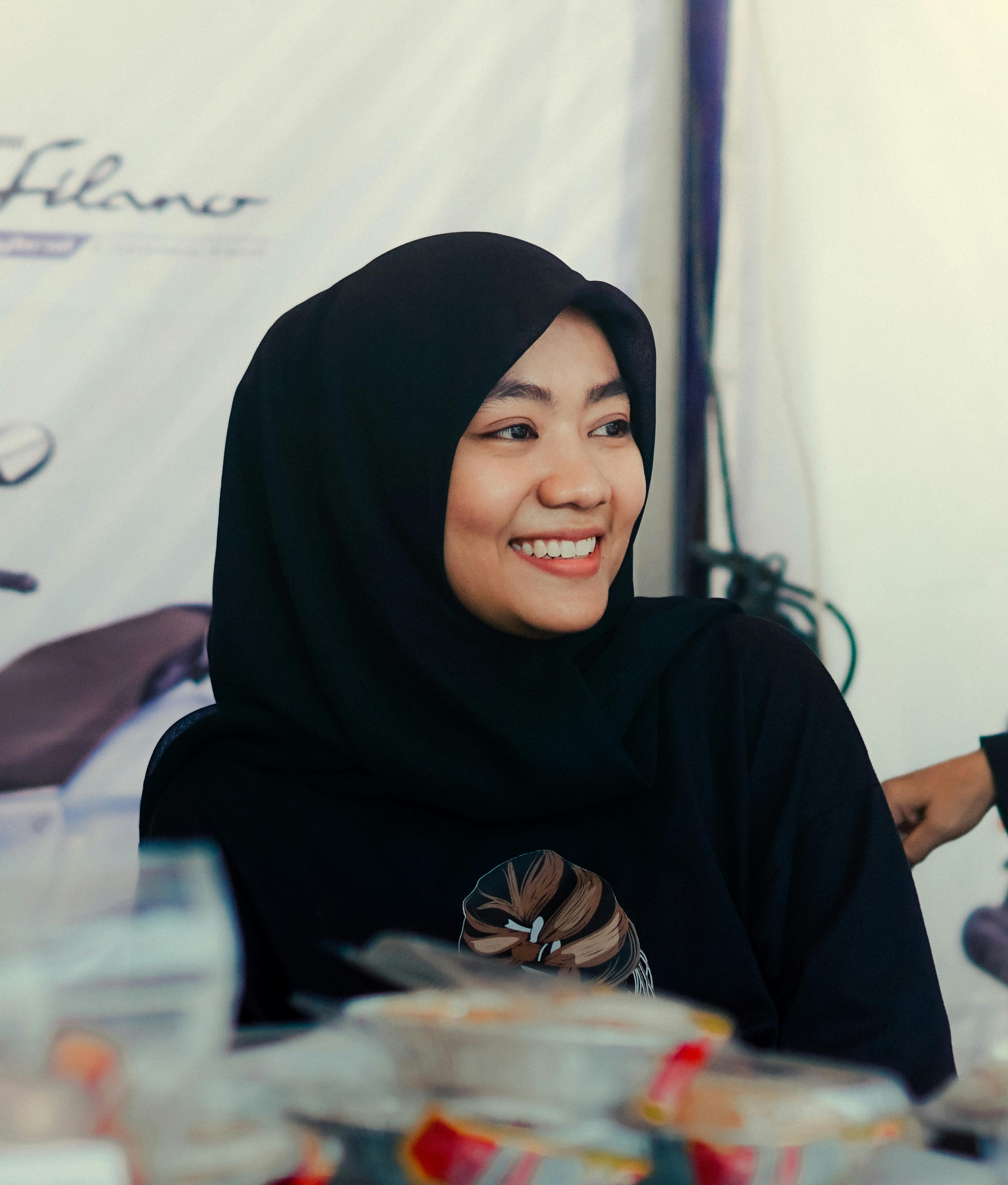 Muslim woman in a black hijab smiling at a market in Serang, Indonesia.