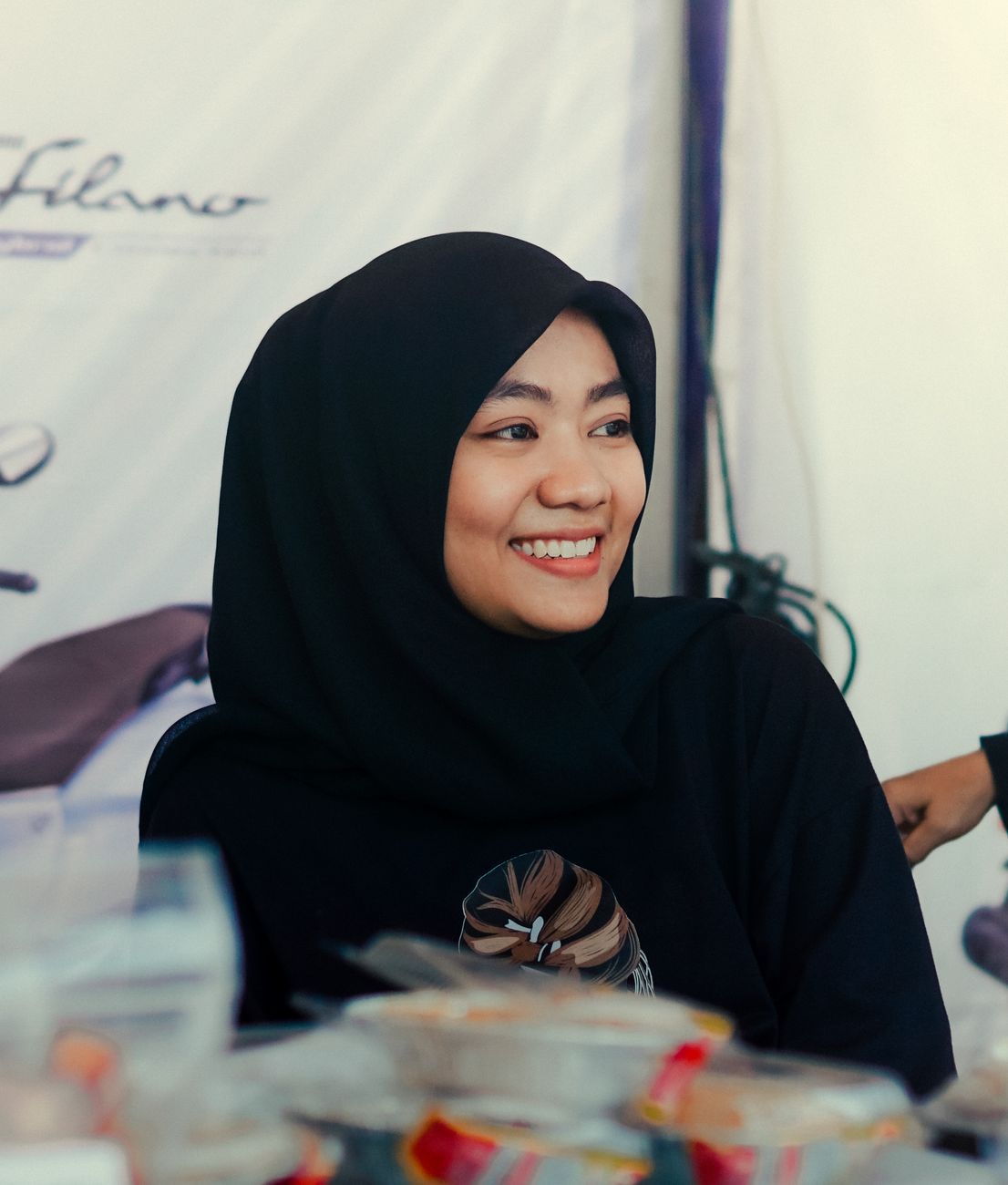 Muslim woman in a black hijab smiling at a market in Serang, Indonesia.