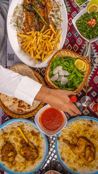 Top view of a Middle Eastern meal setup with grilled fish, rice, and fresh greens.