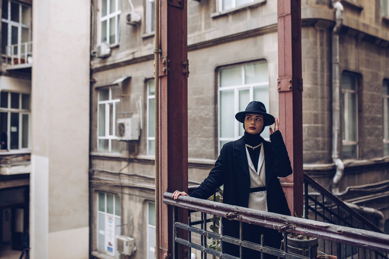 fashionable woman in urban environment wearing a black hat and coat st