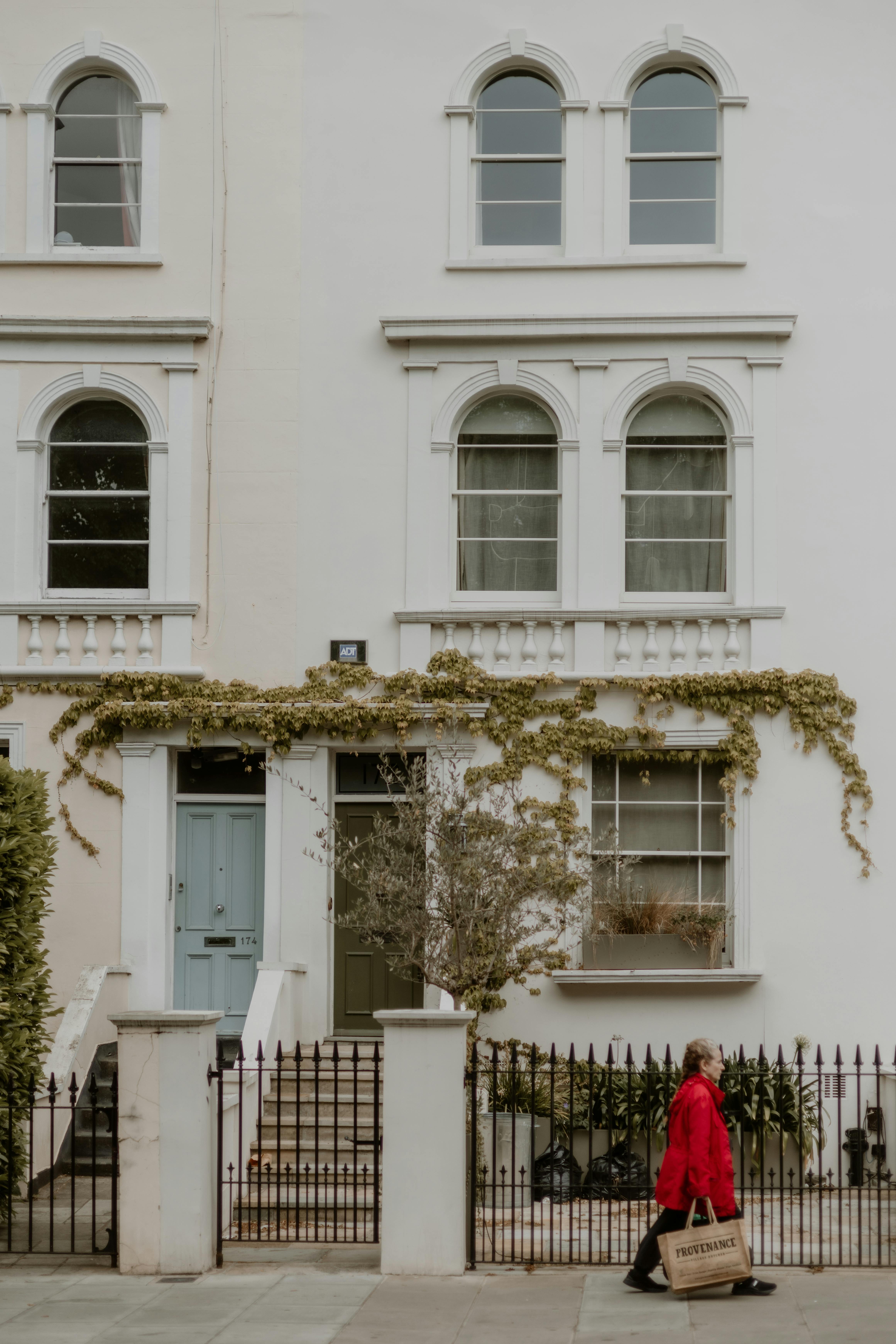 Elegantly designed urban facade with a woman walking past in a vibrant red coat.