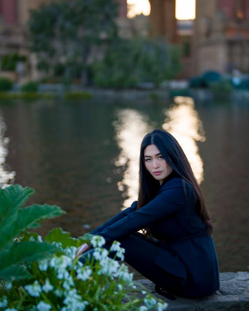 Woman Sitting by River in Town