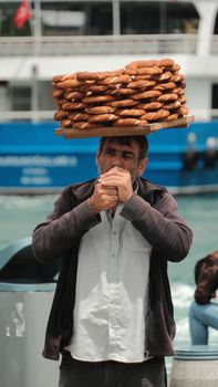 A traditional street vendor balances a tray of simits in a bustling Turkish market.