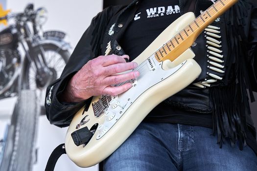 Musician strumming an electric guitar in a rock-themed setting.