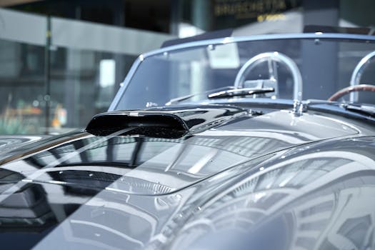 Close-up of a modern car hood reflecting light in a sunlit indoor setting.