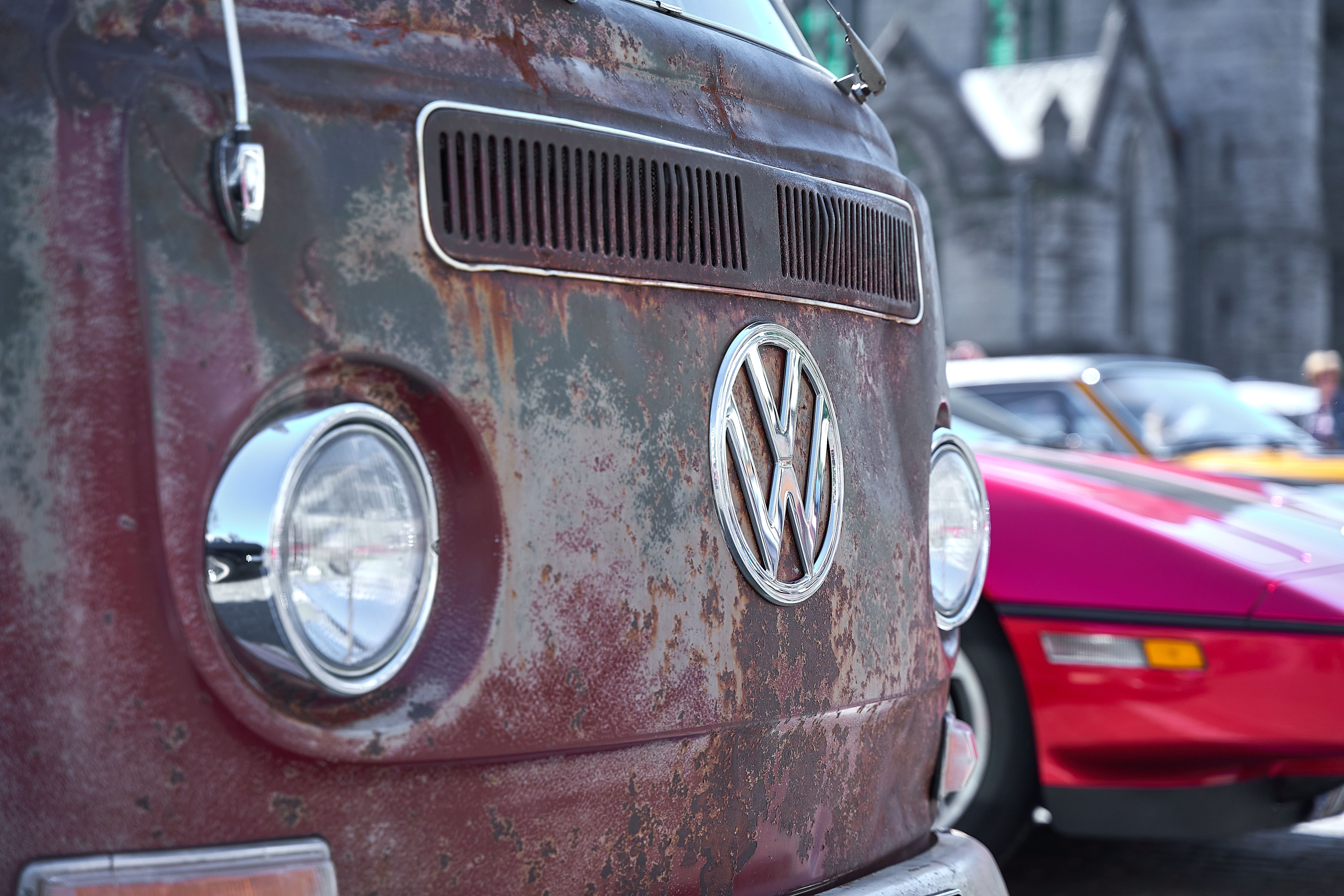 Detailed close-up of a vintage, rusty Volkswagen van parked outdoors, showcasing classic automotive design.