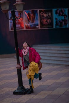 夜晚的城市街头，一位身穿红色夹克的时尚女子在路灯下快乐地摆着姿势