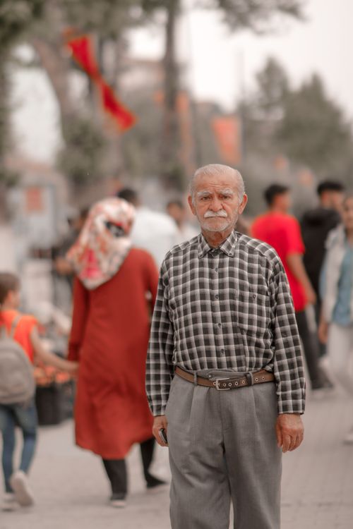 Free Elderly man in plaid shirt walks amidst a vibrant crowd on a sunny day in Malatya, Türkiye. Stock Photo