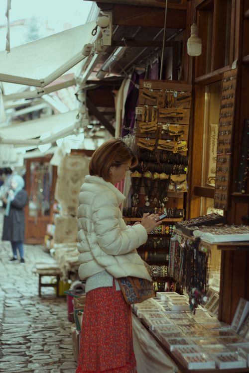 Free Woman browsing at a craft market display of jewelry and gifts, showcasing a traditional setting. Stock Photo