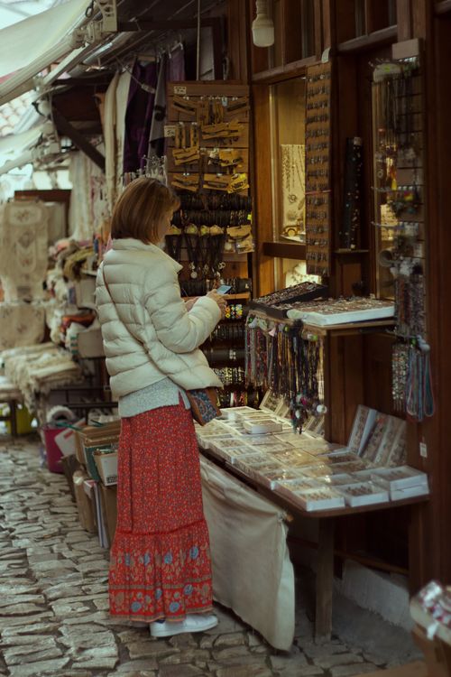 Free Woman exploring a vibrant outdoor artisan market, browsing handmade jewelry. Stock Photo