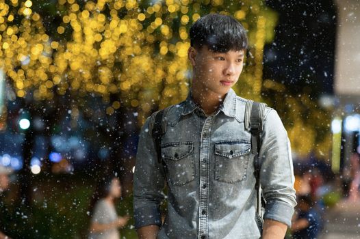 夜晚的雪地里，穿着牛仔夹克的时尚年轻人在城市灯光下摆姿势