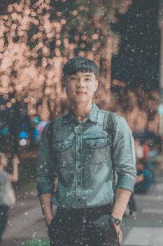Portrait of a young man in a denim shirt, enjoying a festive night outdoors.