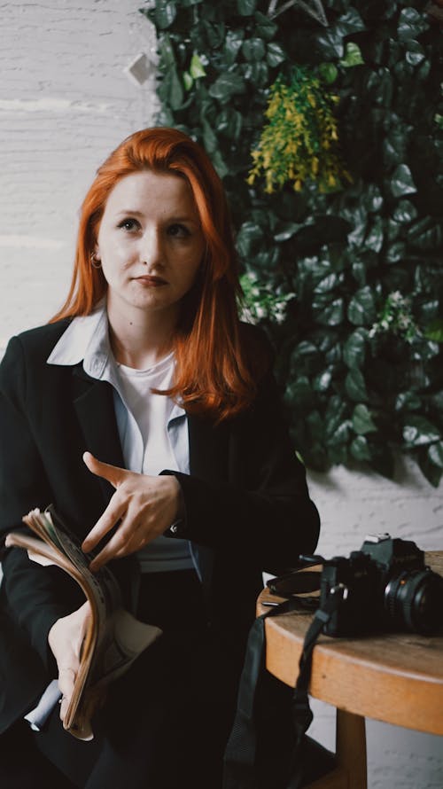 Redhead Woman Sitting by Table with Camera