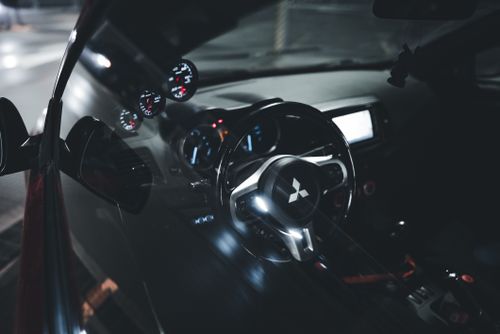 Free A sleek Mitsubishi car interior showcasing an illuminated dashboard and steering wheel, captured at night. Stock Photo