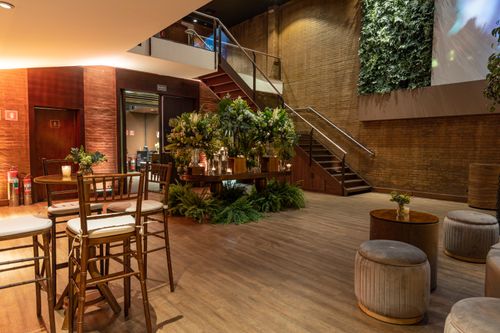 Free Stylish indoor lounge area featuring a staircase, lush plants, and elegant furniture in a warm setting. Stock Photo