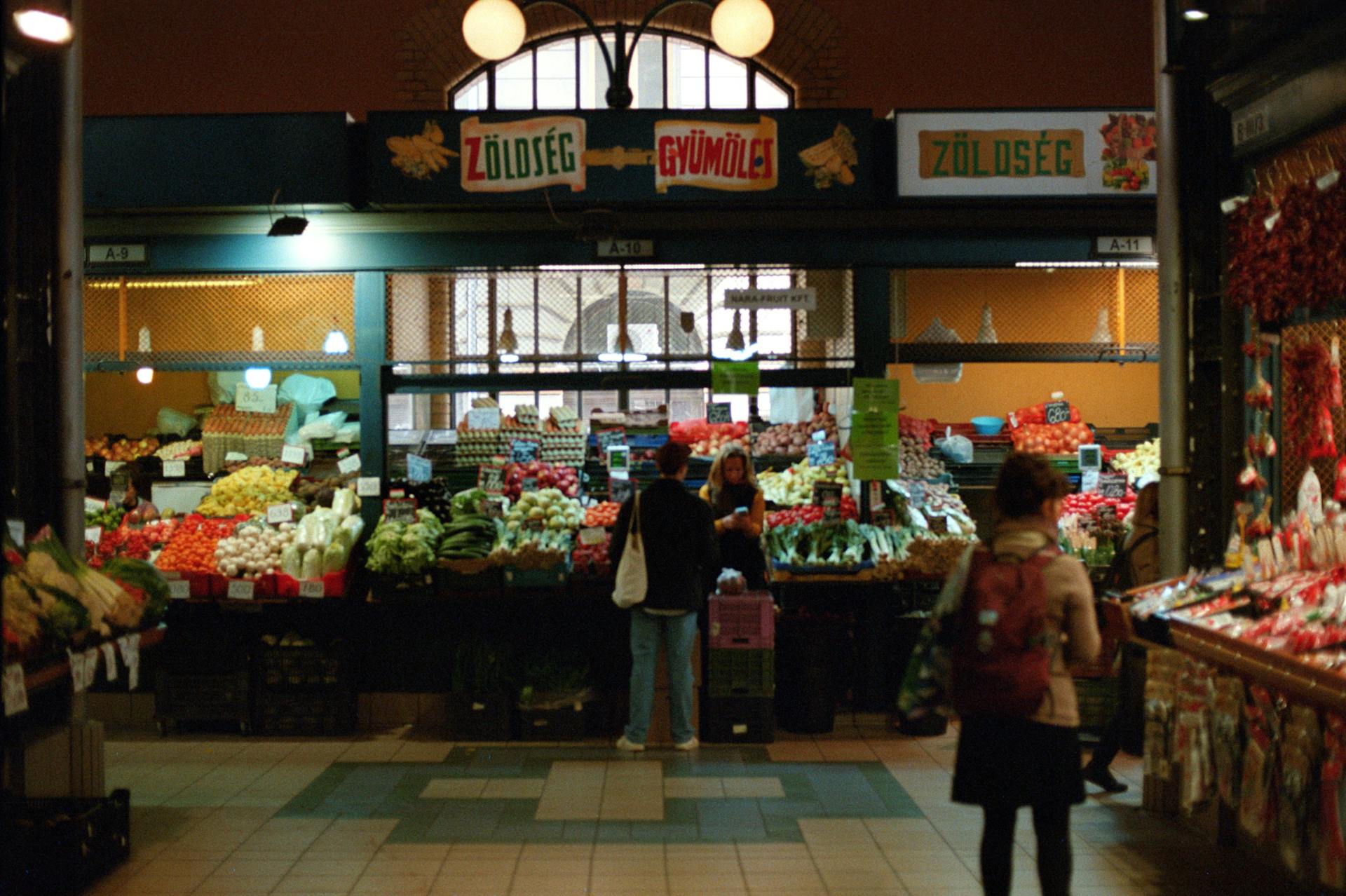 Vibrant scene inside Budapest's Central Market Hall with shoppers and colorful produce.