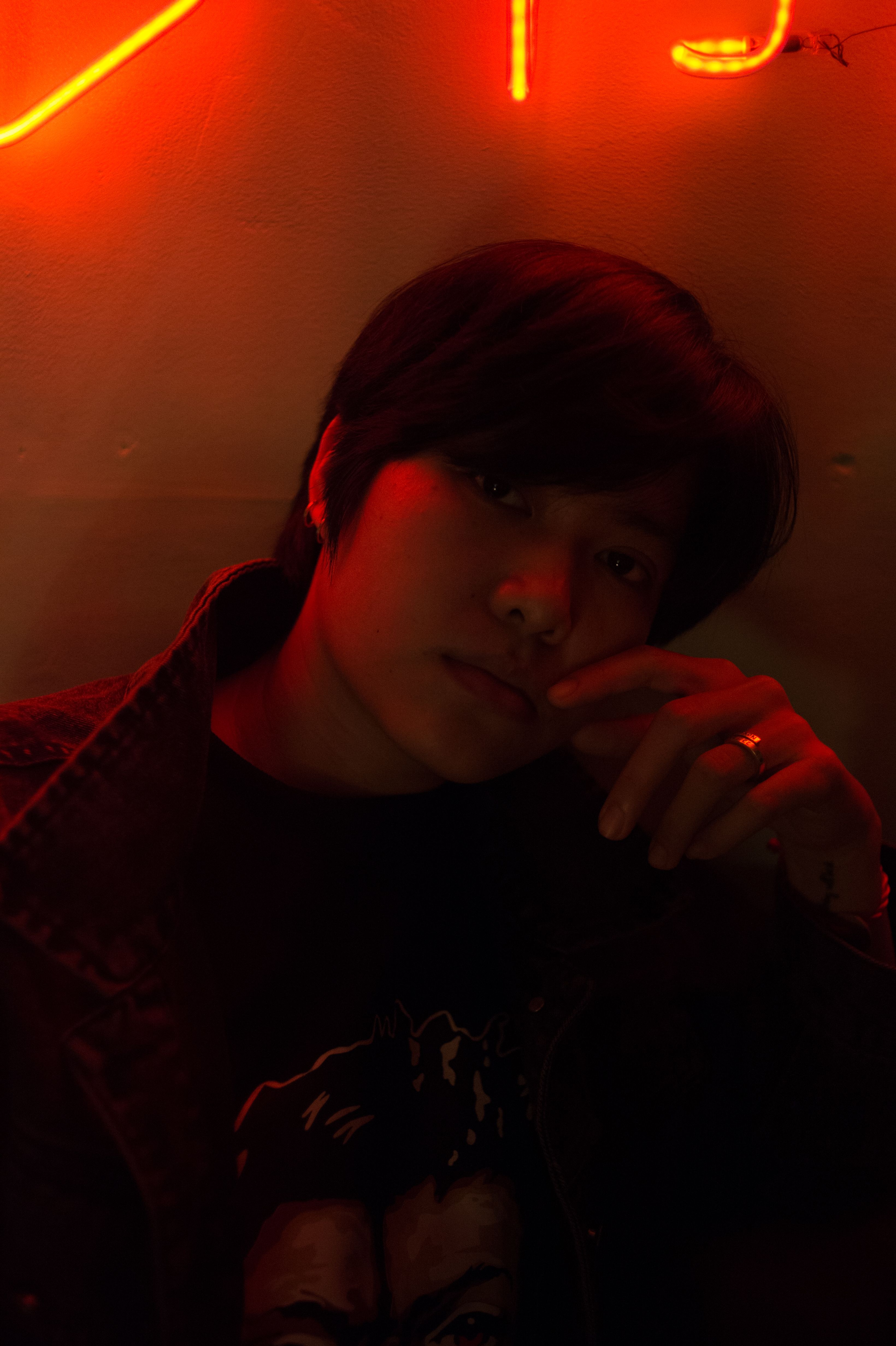 Artistic portrait of a person with red neon lighting, creating a dramatic and moody atmosphere.