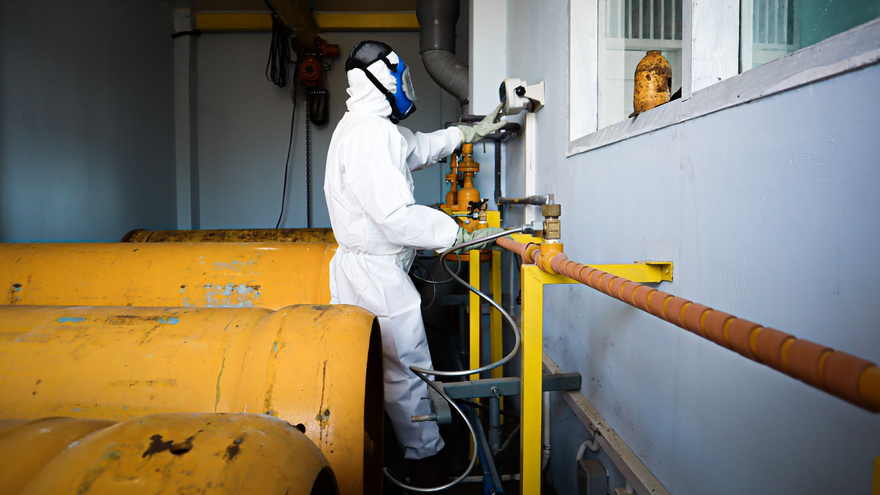 Environmental professional working in protective equipment inside an industrial facility