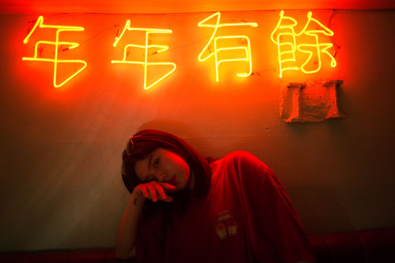 young woman posing under vibrant neon signs dark artistic indoor setti