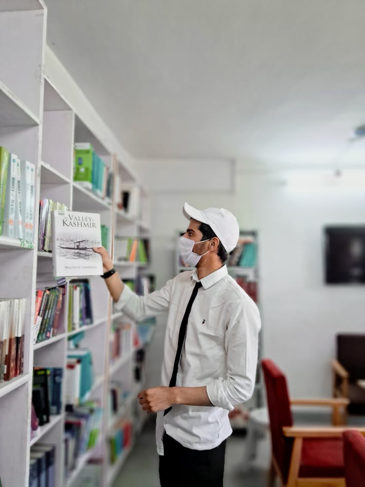 Man In Cap And Mask Standing With Book