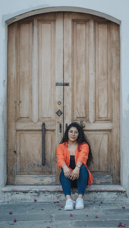 Young Woman Sitting in front of Old Wooden Door 