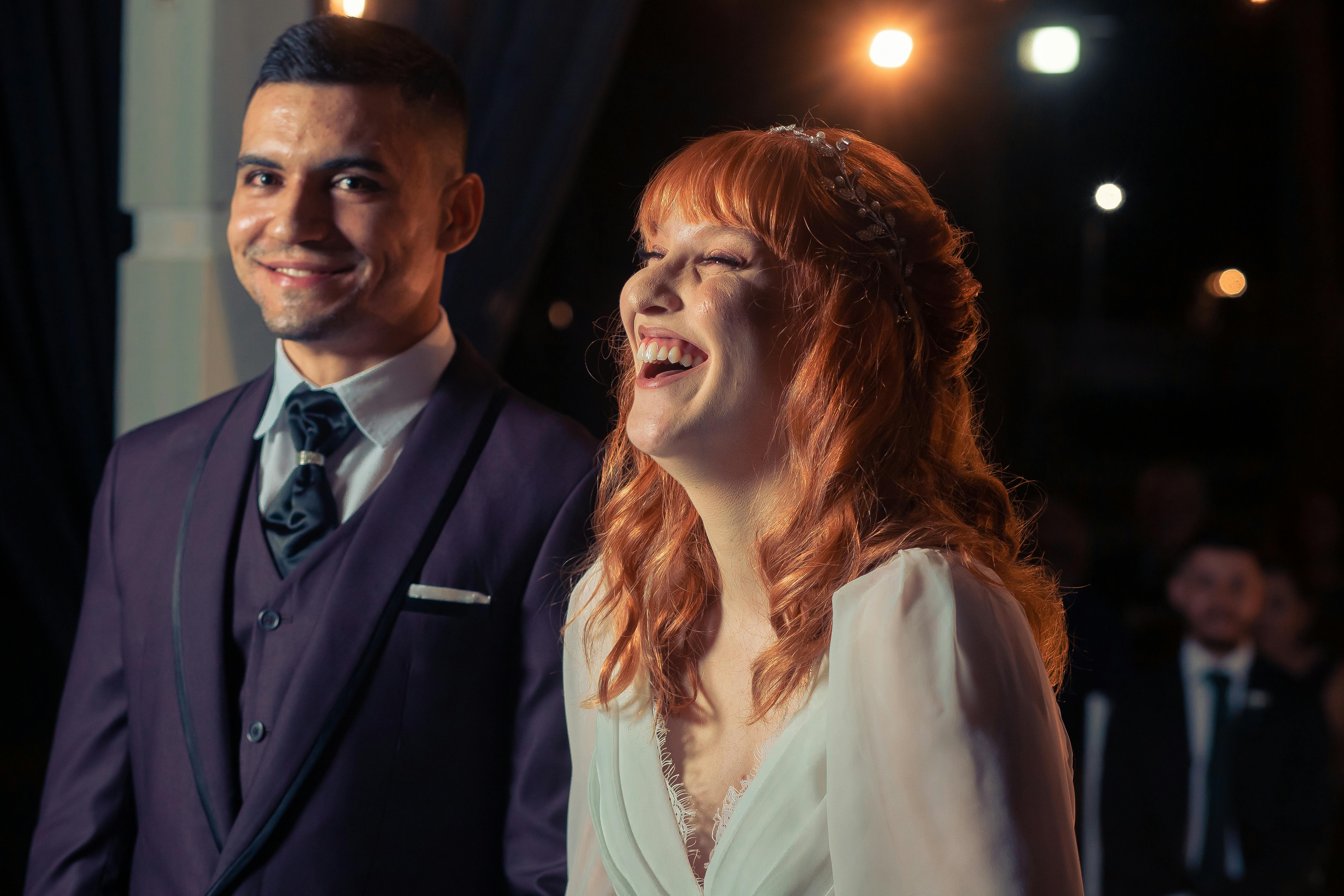 Smiling bride and groom enjoy their wedding evening, captured with warm tones highlighting their happiness.