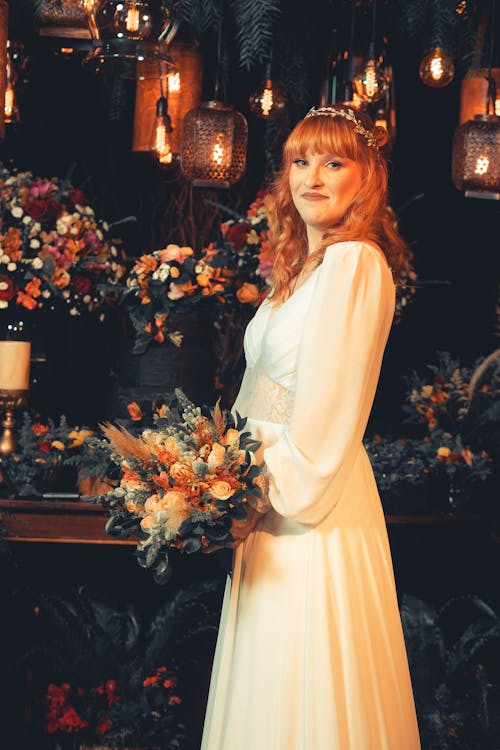 Bride Holding a Bouquet and Standing on the Background of a Flowers Arrangement