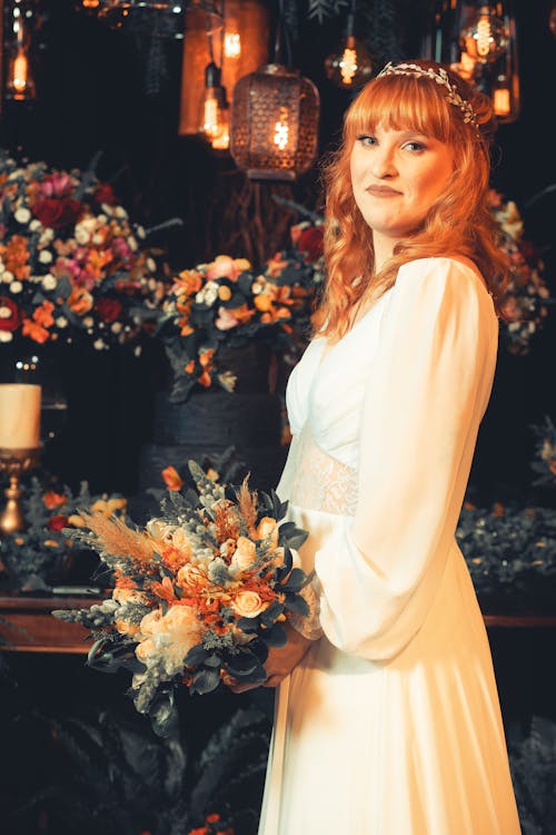 Bride Holding a Bouquet and Standing on the Background of a Flowers Arrangement
