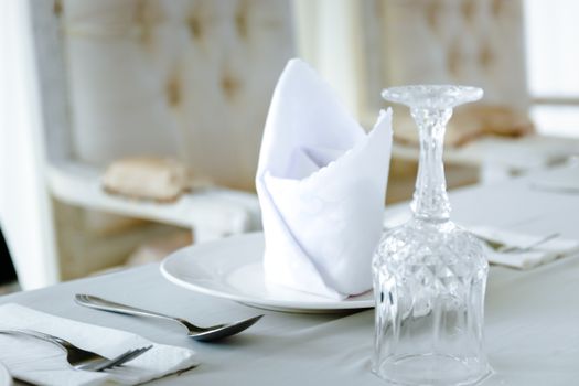 Close-up of an elegant table setting featuring a crystal glass and folded napkin on a plate.