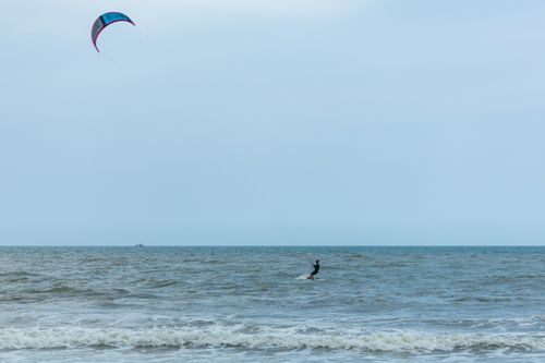 Free Experience the thrill of kitesurfing on a vast ocean under clear skies with this action-packed scene. Stock Photo