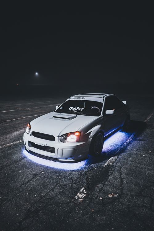 Free A white modified Subaru sports car with neon lights parked at night. Stock Photo