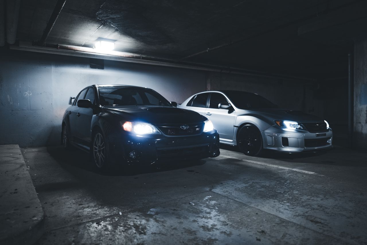 subaru wrx and impreza parked in a dimly lit underground garage