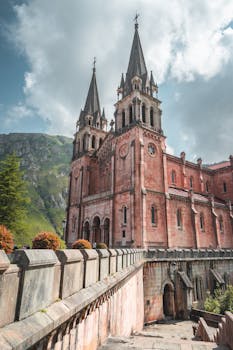 Gothic-style Basilica of Santa María la Real in Covadonga, Spain, nestled against mountainous landscapes.