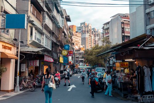 Free People walking through a bustling street market surrounded by tall urban buildings. Stock Photo