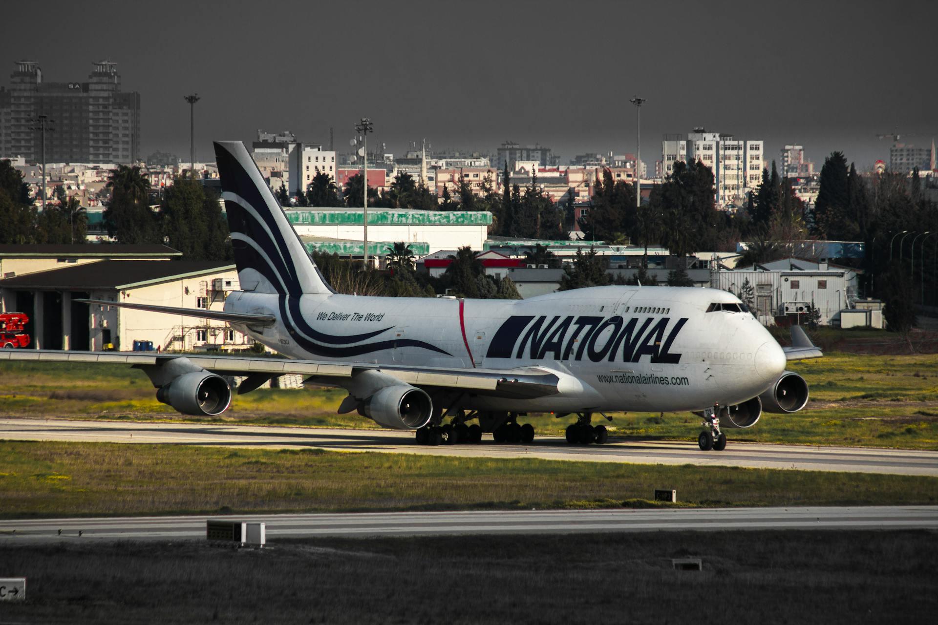National Airlines Boeing 747 airplane on the tarmac with urban skyline backdrop.