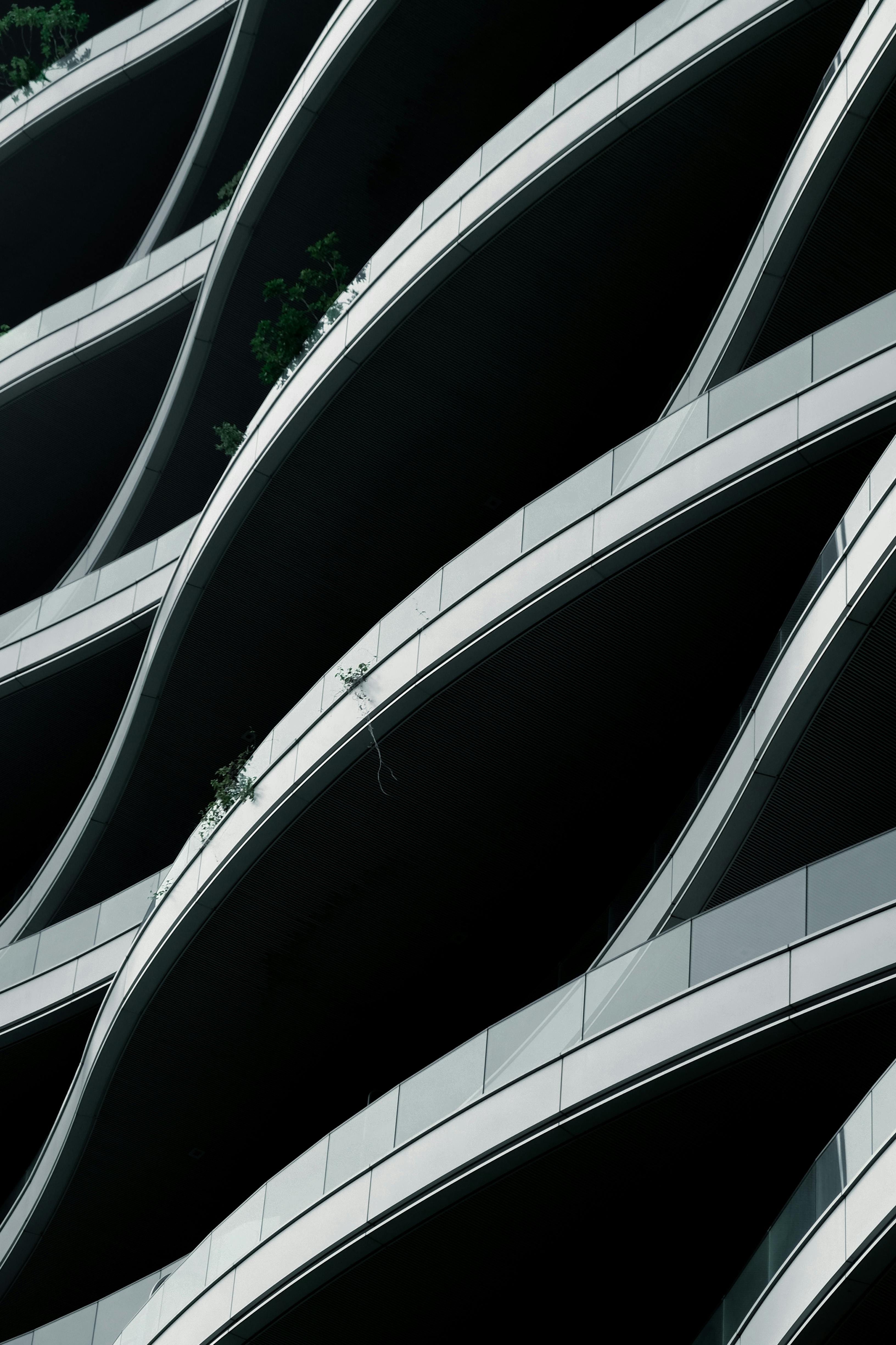 Vertical shot of a modern building facade with curved glass and metal railings.