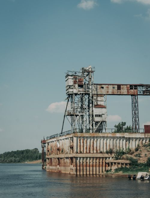 Free Abandoned industrial structure by a river, showcasing urban decay and rust. Stock Photo