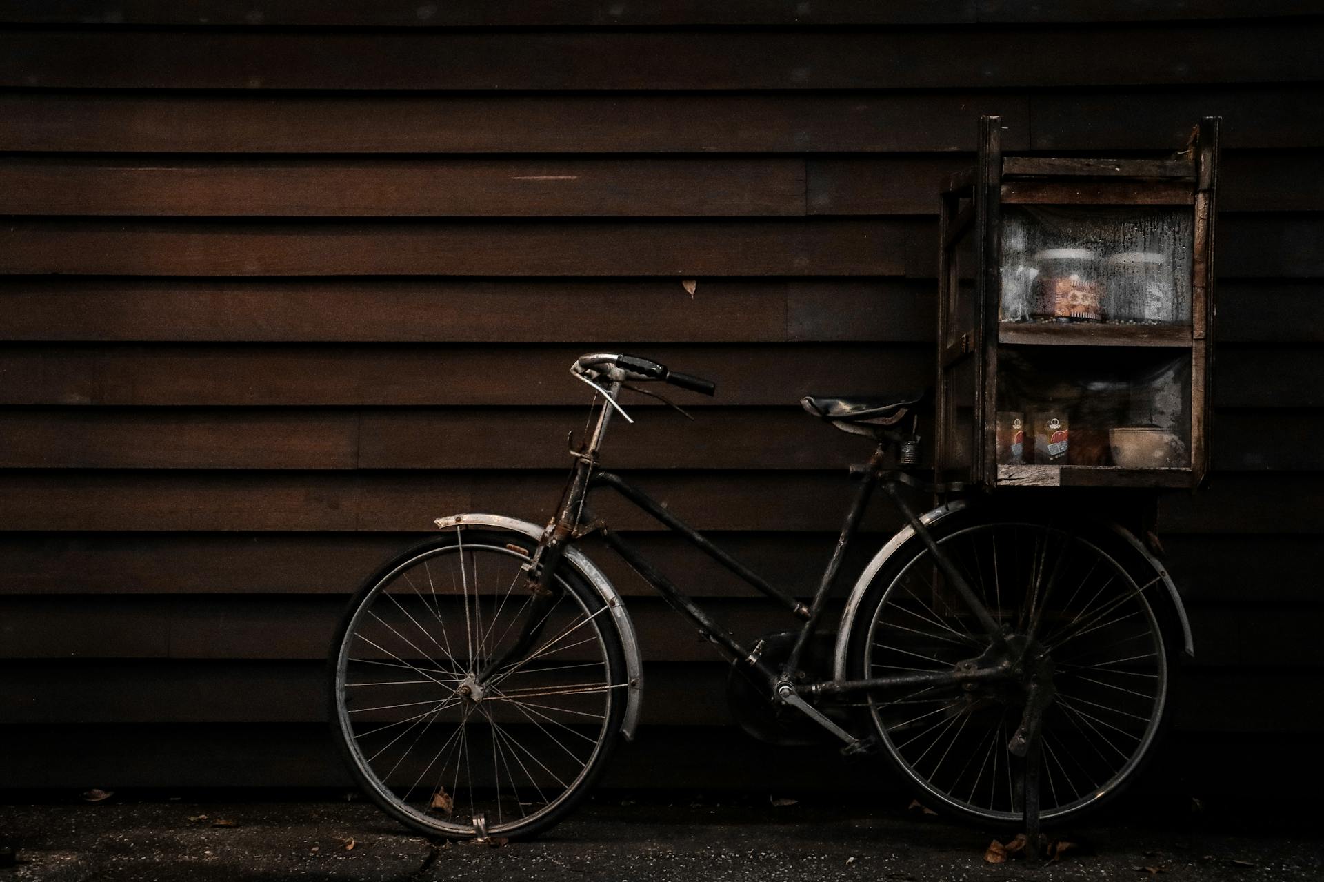 A vintage bicycle with a wooden box against a dark wooden wall, evoking nostalgia.