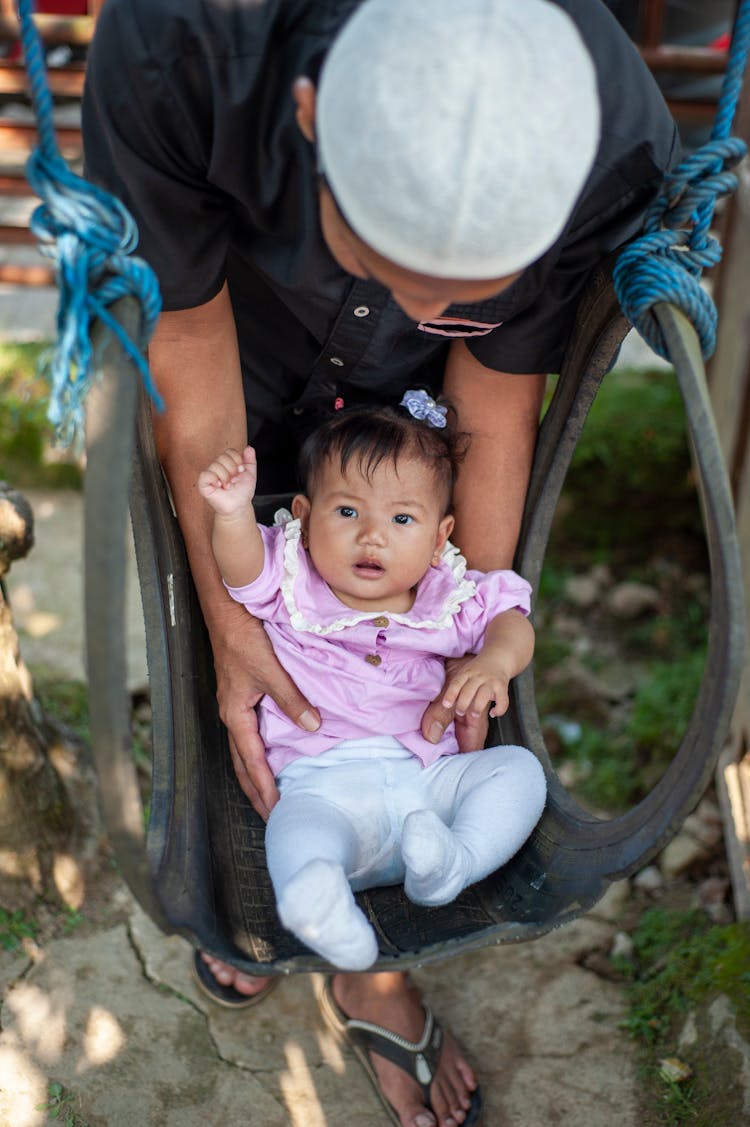 Man Swinging Baby On Playground