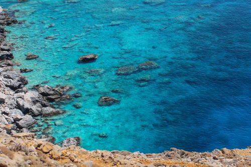Free Crystal-clear turquoise waters and rocky coastline in Rethymno, Greece, perfect for travel inspiration. Stock Photo